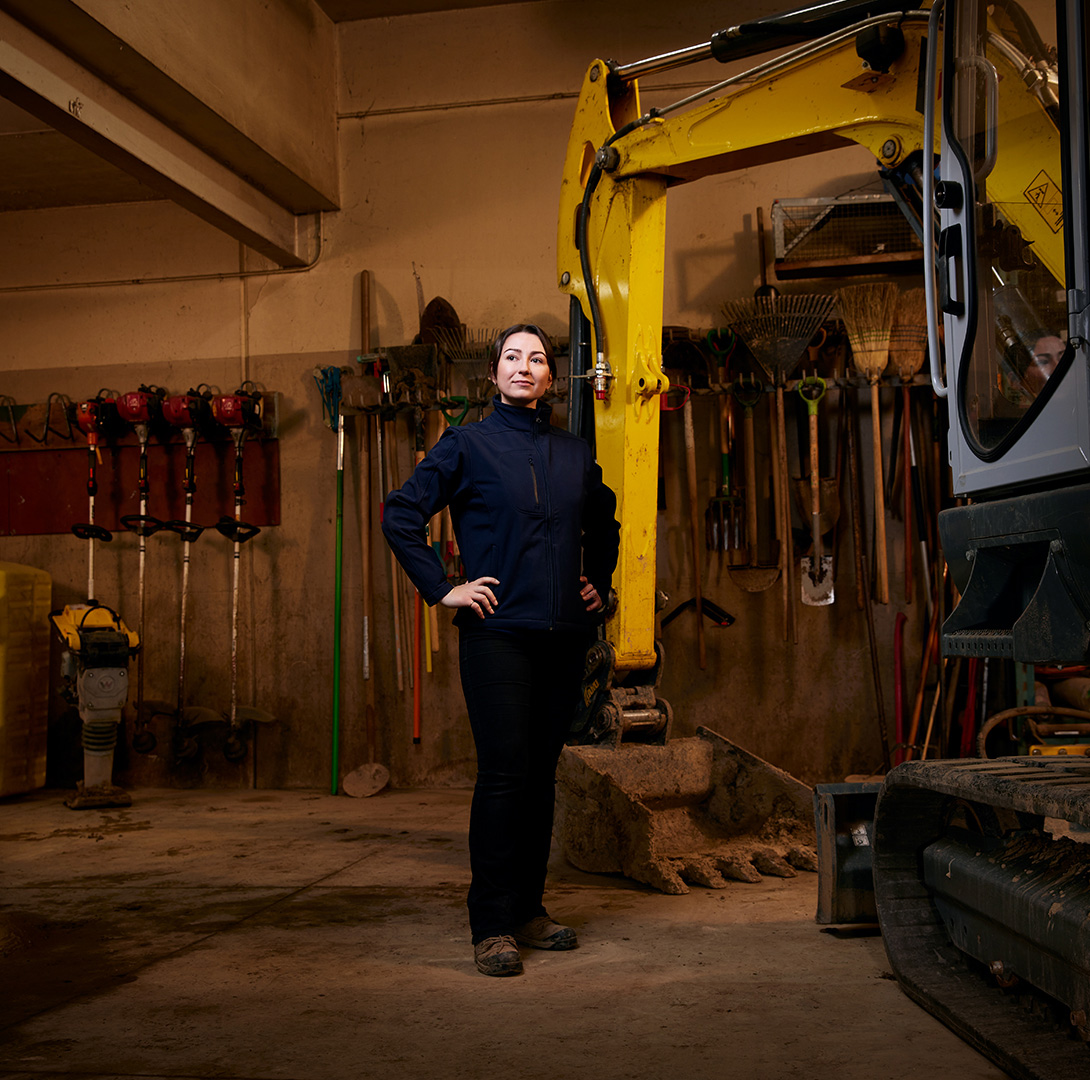 Opérateur de cimetière debout devant des outils et des machines d'entretien du terrain.
