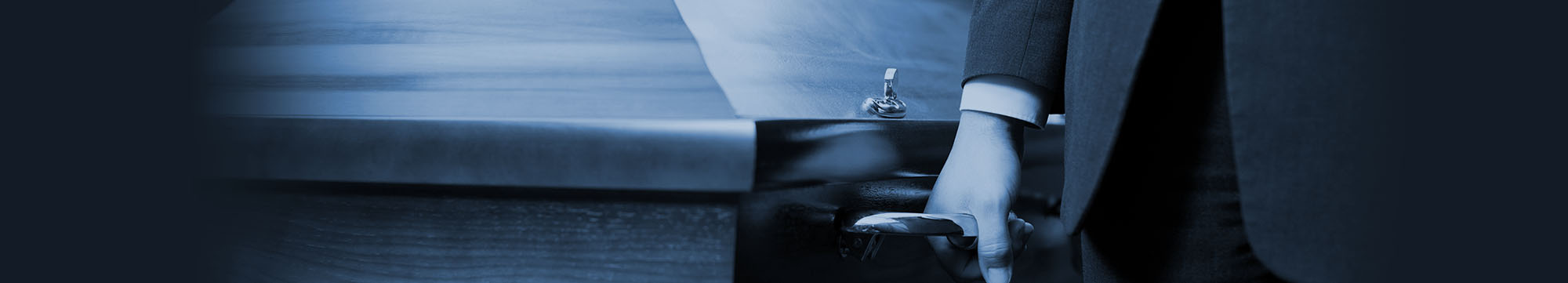 Funeral Assistant acting as Pall Bearer carrying a wooden casket.
